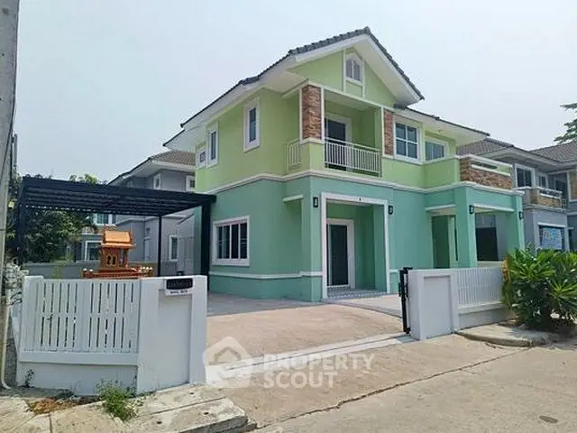 Charming two-story green house with modern design and spacious driveway in a serene neighborhood.