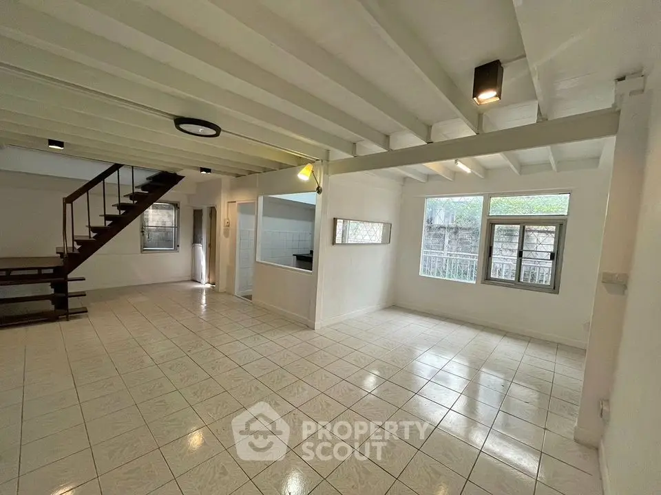 Spacious open-plan living area with staircase and large windows in modern home