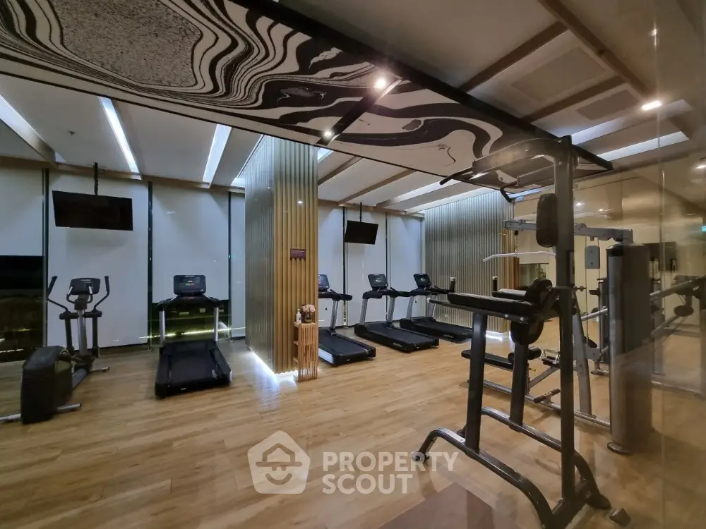 Luxurious gym with modern equipment and stylish design in upscale residential building.