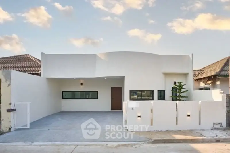 Modern minimalist single-story house with sleek white facade and spacious driveway.