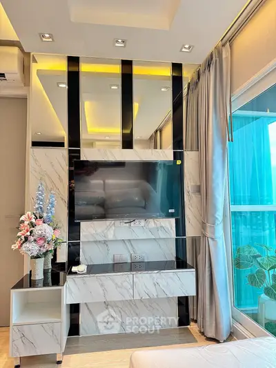 Luxurious modern living room with marble accents and large TV, featuring elegant decor and floor-to-ceiling windows.