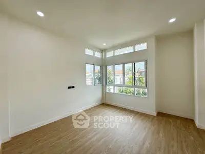 Spacious empty room with large windows and wooden flooring, perfect for customization.