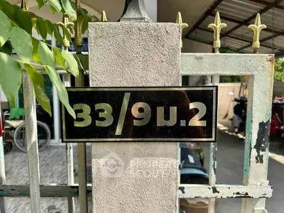 Residential property entrance with address plaque on gatepost, showcasing secure and inviting entryway.