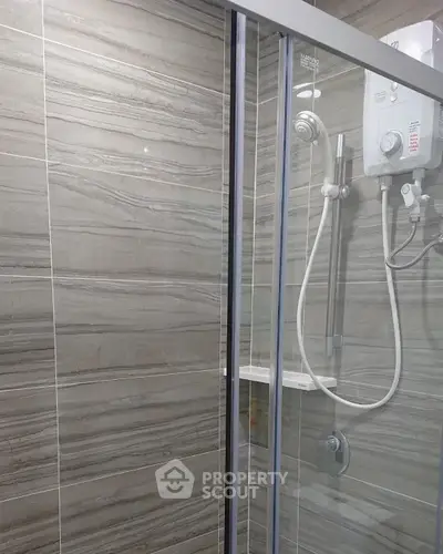 Modern bathroom with sleek shower enclosure and electric water heater.