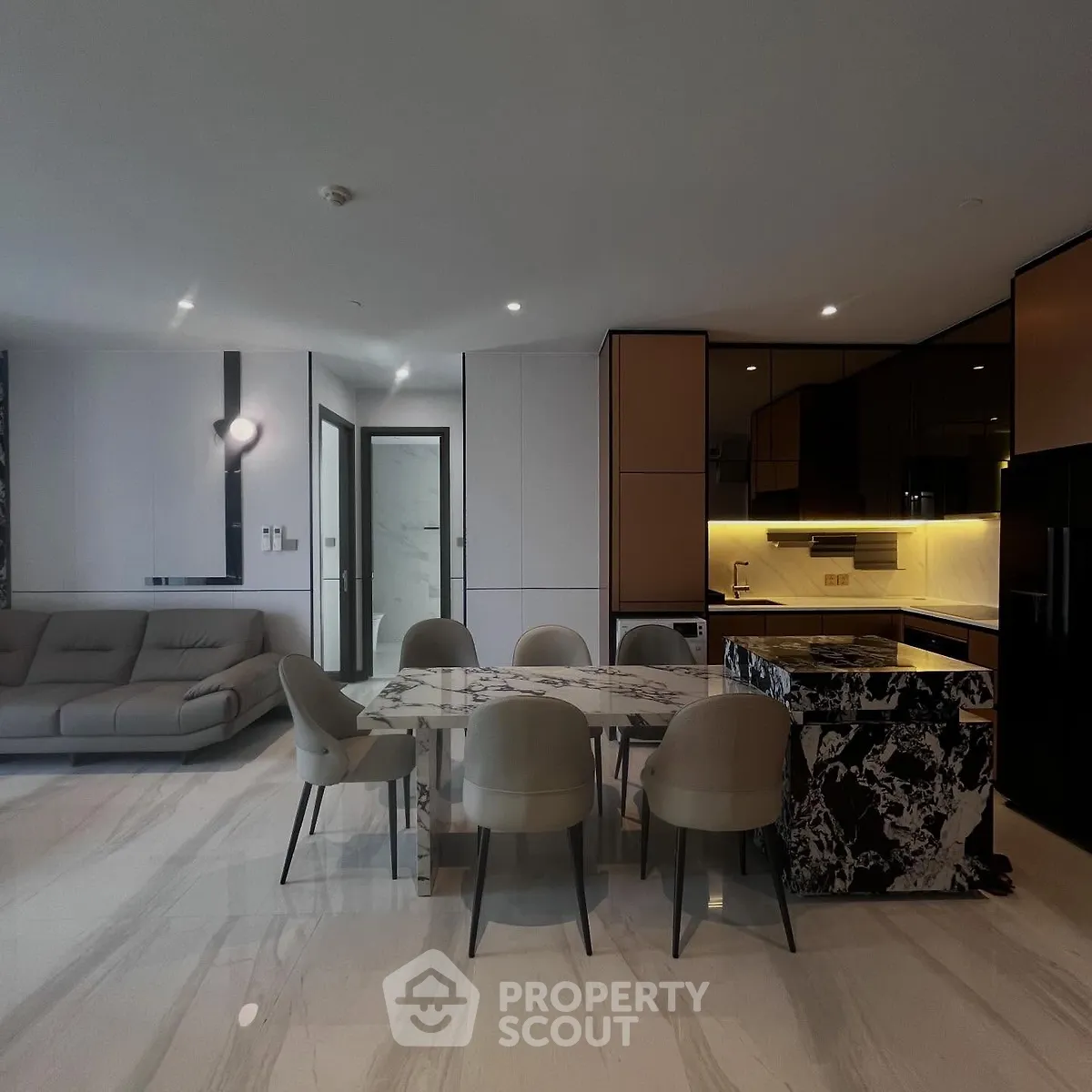 Luxurious modern open-plan living room and kitchen with marble flooring and elegant furniture.
