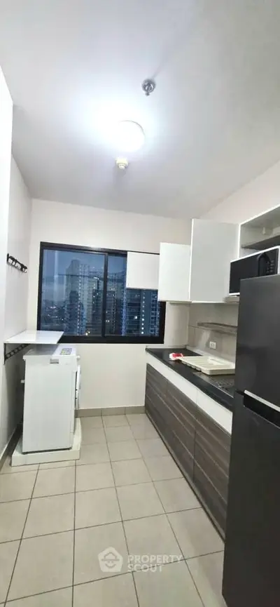Modern kitchen with sleek cabinets and city view window, featuring a washing machine and refrigerator.