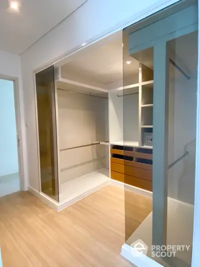 Spacious walk-in closet with custom shelving and mirrored sliding doors, enhancing the bright, modern feel of this well-designed storage space.