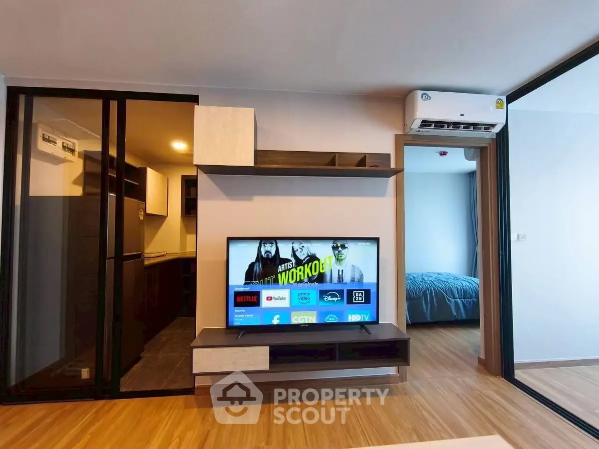 Modern living room with TV, air conditioning, and view into bedroom and kitchen.