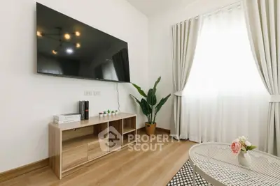 Modern living room with large TV, stylish furniture, and natural light.