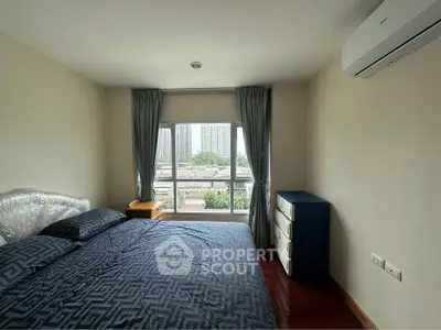 Spacious bedroom with large window offering city views, featuring modern furnishings and air conditioning.