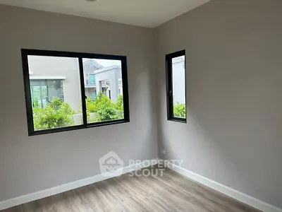 Spacious empty room with large windows and wooden flooring, ideal for customization.