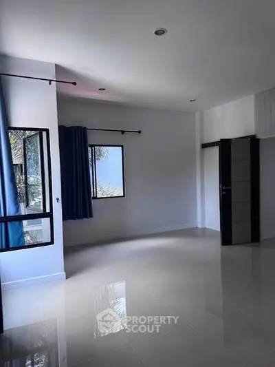 Spacious empty room with glossy tiled floor and large windows, perfect for customization.