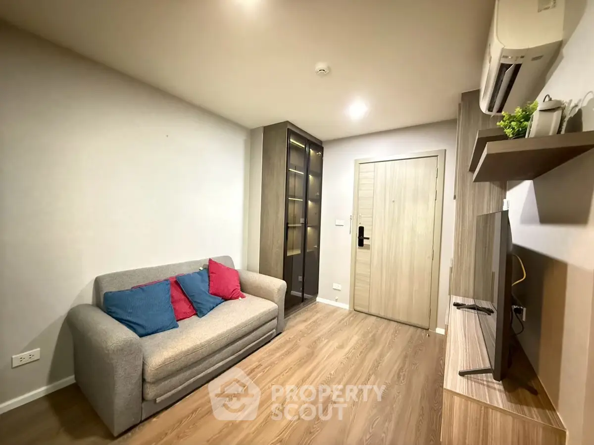 Modern living room with cozy sofa, stylish TV unit, and sleek wooden flooring in a contemporary apartment.