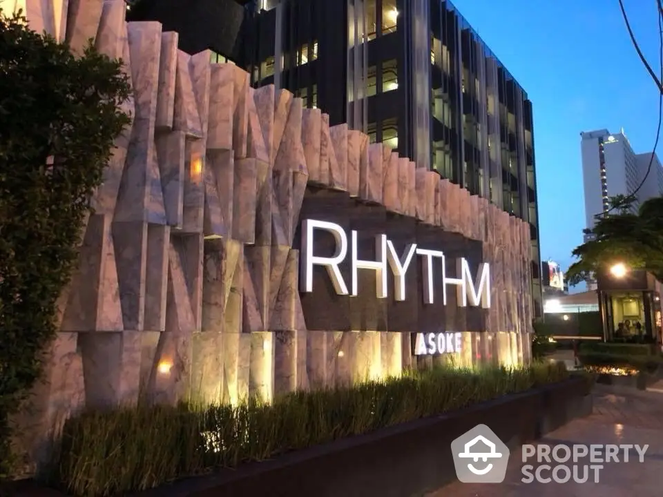 Modern luxury condominium exterior with illuminated signage at dusk, showcasing architectural elegance.