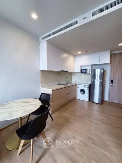 Modern kitchen with sleek appliances and dining area in a stylish apartment.