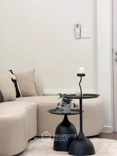 Modern living room with stylish beige sofa and sleek black side tables, perfect for contemporary home decor.
