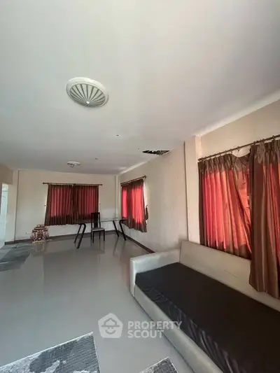 Spacious living room with modern sofa and large windows, ideal for natural light.