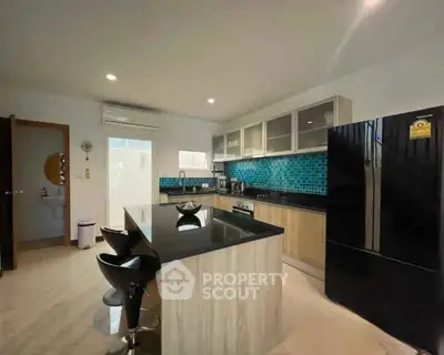 Modern kitchen with island, sleek black appliances, and stylish blue backsplash