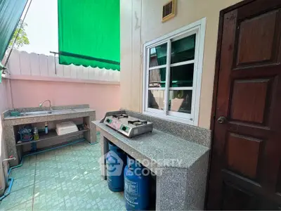 Charming outdoor kitchen with gas stove and sink, perfect for alfresco dining.