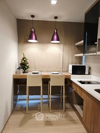 Modern kitchen with stylish lighting and compact dining area, perfect for cozy meals.