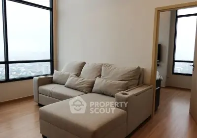 Spacious living room with large windows and cozy beige sofa in modern apartment.