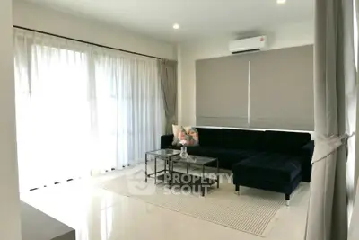 Modern living room with sleek black sofa and large windows