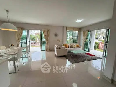 Spacious open-plan living room with modern decor and large windows offering garden views.