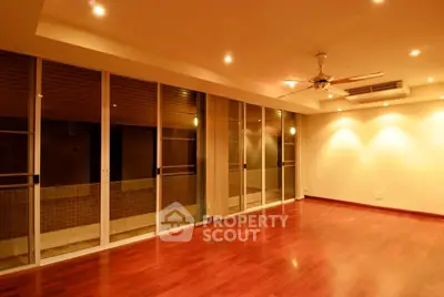 Spacious living room with hardwood floors and ceiling fan in modern apartment.