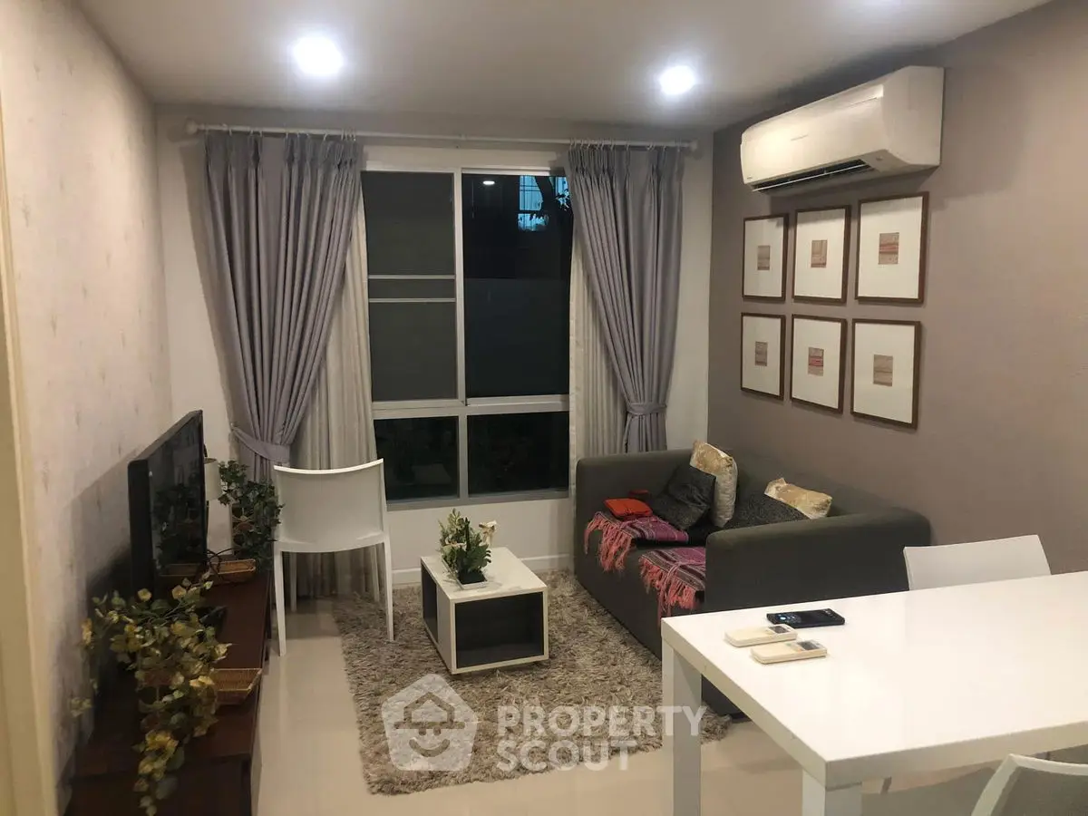 Cozy living room with modern decor, air conditioning, and natural light from large window.