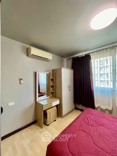 Cozy bedroom with air conditioning and natural light, featuring a stylish vanity and wardrobe.