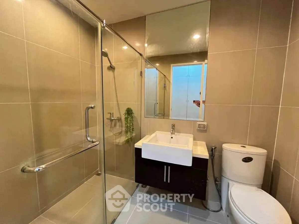 Modern bathroom with glass shower and sleek fixtures in contemporary apartment.