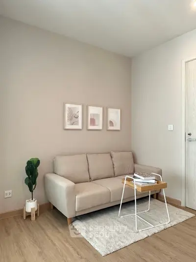 Modern living room with beige sofa, minimalist decor, and wooden flooring.