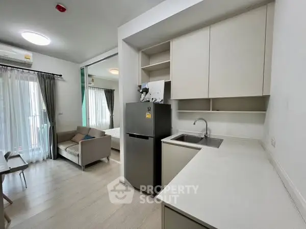 Modern open-layout kitchen with sleek cabinetry and stainless steel appliances in a stylish apartment.