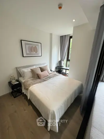 Modern bedroom with stylish decor and large window offering natural light.