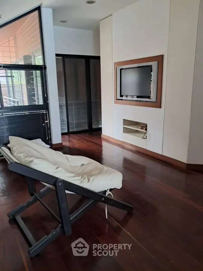 Modern living room with sleek wooden flooring and built-in TV unit