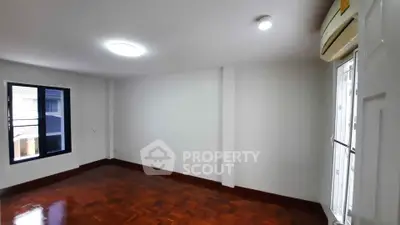 Spacious empty room with wooden flooring and large window, perfect for customization.