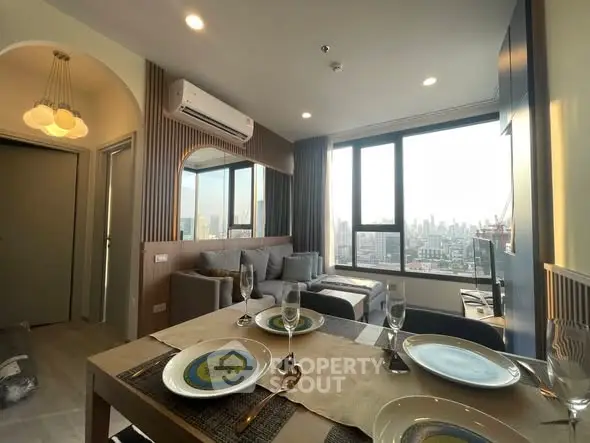 Modern living room with city view, stylish decor, and dining area in a high-rise apartment.