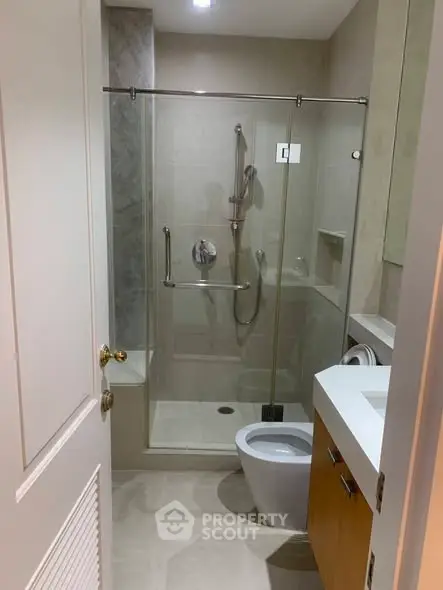 Modern bathroom with glass shower enclosure and sleek fixtures in a contemporary apartment.
