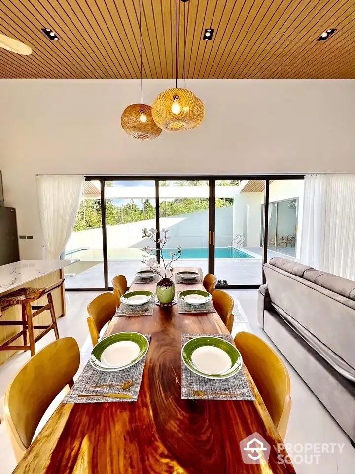 Luxurious dining area with pool view, elegant wooden table, and modern lighting in open layout home.