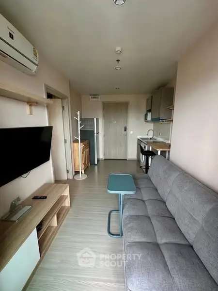 Modern living room with sleek furniture and open kitchen layout in cozy apartment.