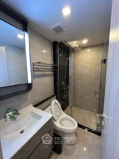 Modern bathroom with sleek design, featuring a glass shower enclosure and elegant fixtures.