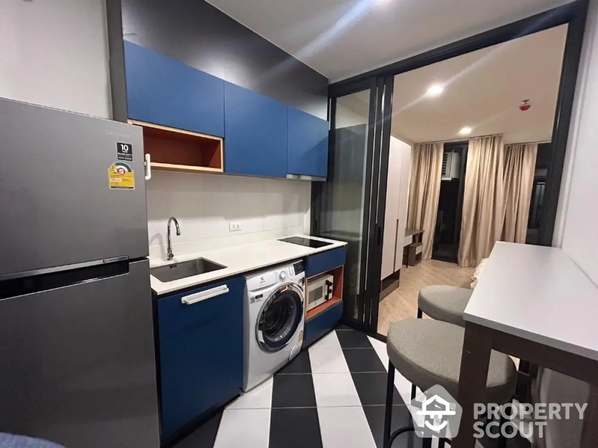 Modern kitchen with washing machine and sleek blue cabinets in stylish apartment