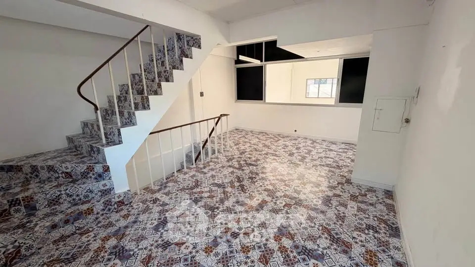 Spacious interior with unique patterned flooring and staircase, ideal for creative living space.