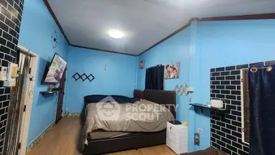 Cozy bedroom with blue walls, modern decor, and wall-mounted TV for a comfortable living experience.