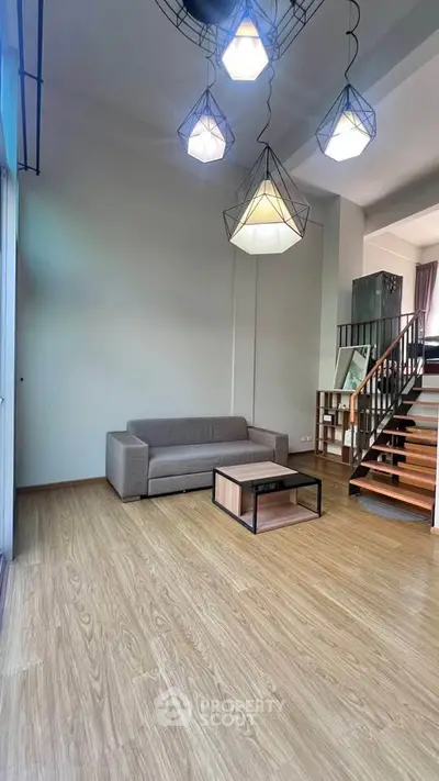 Modern living room with stylish lighting and wooden staircase in a spacious apartment.