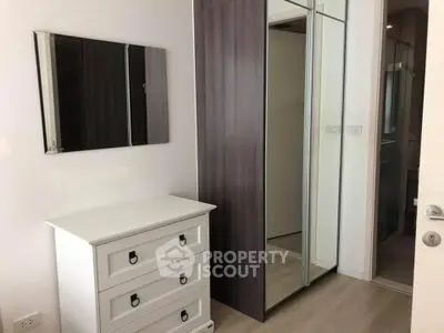 Modern bedroom with sleek mirrored wardrobe and elegant white dresser.