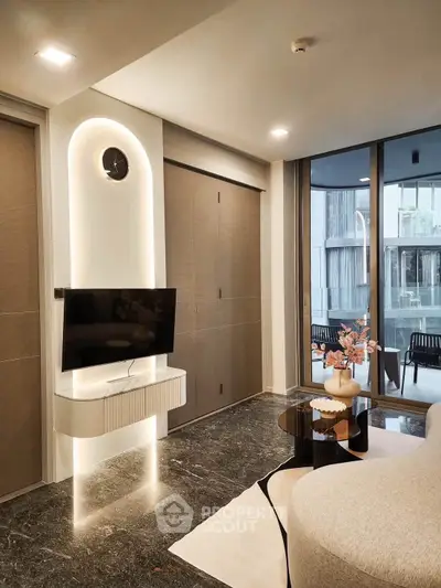 Modern living room with sleek TV setup and large windows overlooking balcony.