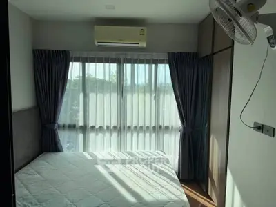 Cozy bedroom with large window and air conditioning, featuring modern curtains and ample natural light.
