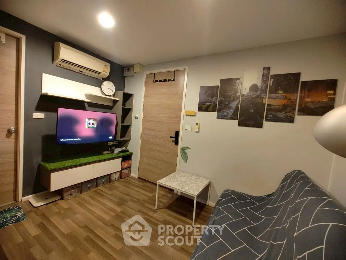 Cozy living room with modern decor and wall art, featuring a flat-screen TV and stylish furniture.