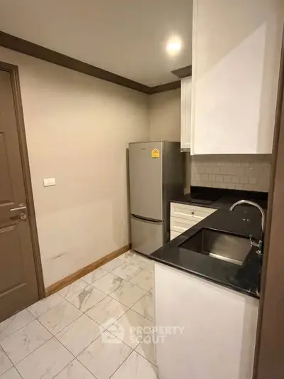Compact kitchen with modern appliances and sleek design in a cozy apartment.